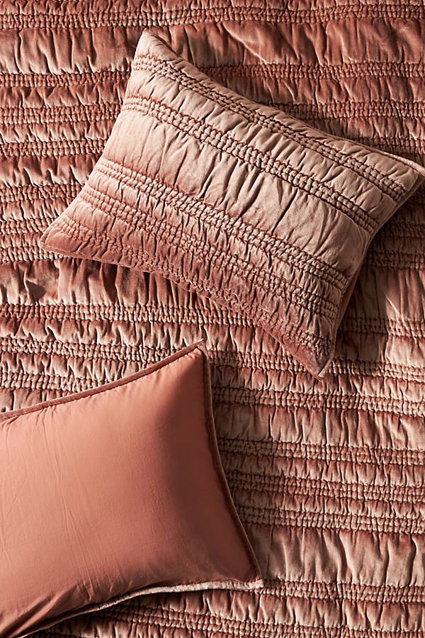 two pillows on top of a bed with pink sheets and pillow cases in the background