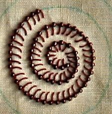 an image of a spiral design made out of beaded beads on a piece of cloth