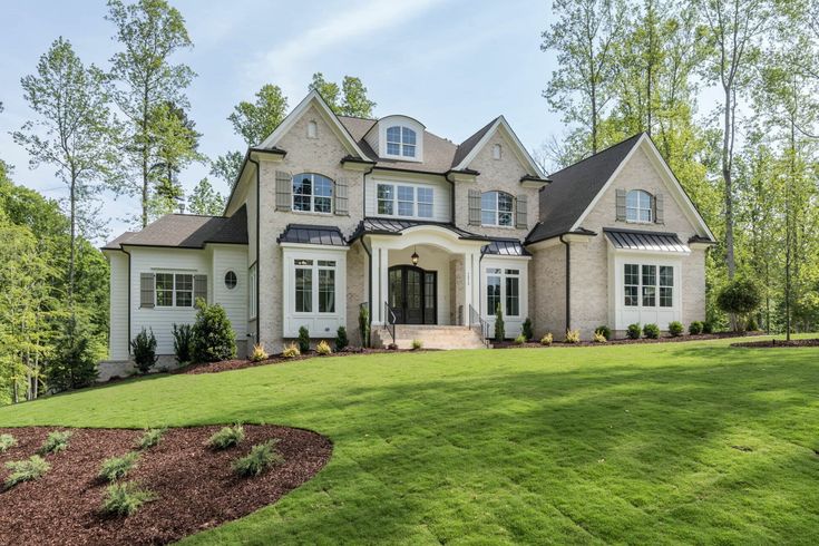 a large white house sitting on top of a lush green field in front of trees