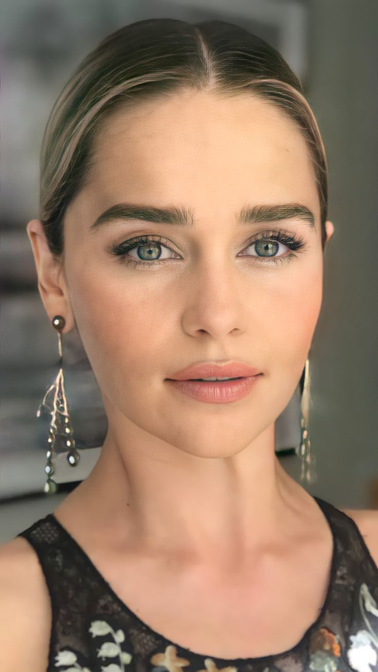 a woman with blue eyes and earrings on her head is looking at the camera while wearing black