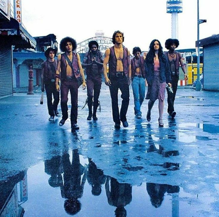 a group of people walking across a wet parking lot