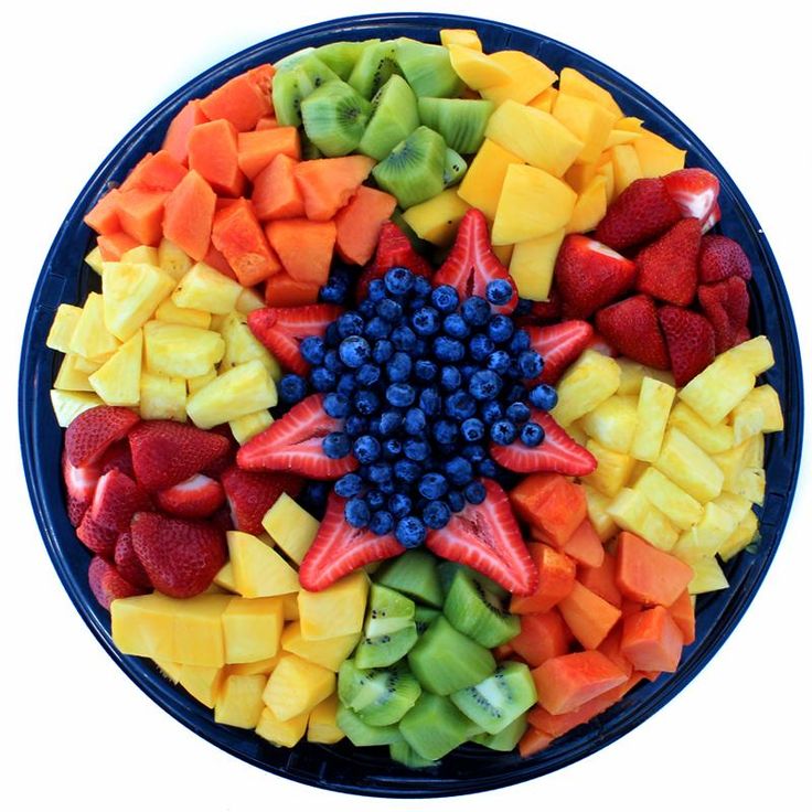 a blue plate topped with cut up fruits and berries in the shape of a star