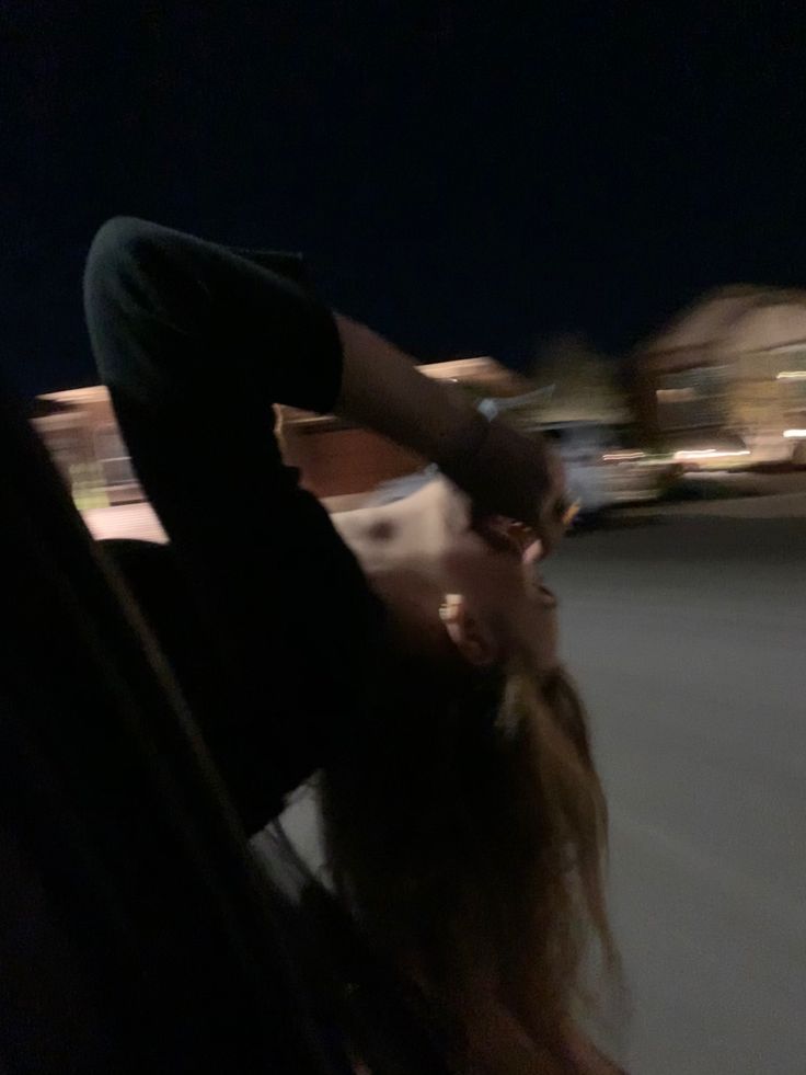 a woman riding on the back of a bus at night