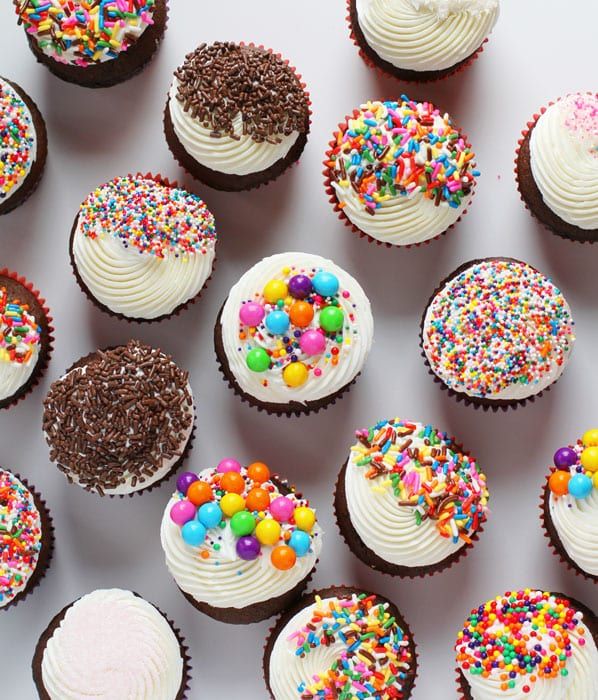 many cupcakes with white frosting and sprinkles