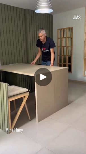 a man standing in front of a kitchen counter top next to a chair and table