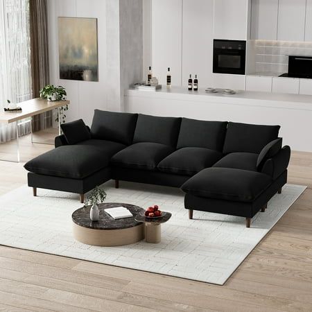 a black sectional sofa sitting on top of a white rug