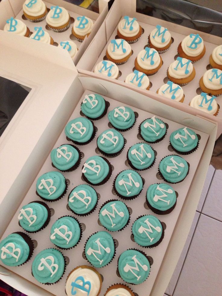 cupcakes with blue and white frosting are in a box on the table