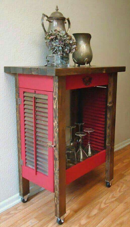 a red cabinet with two silver vases on top and a wooden table underneath it