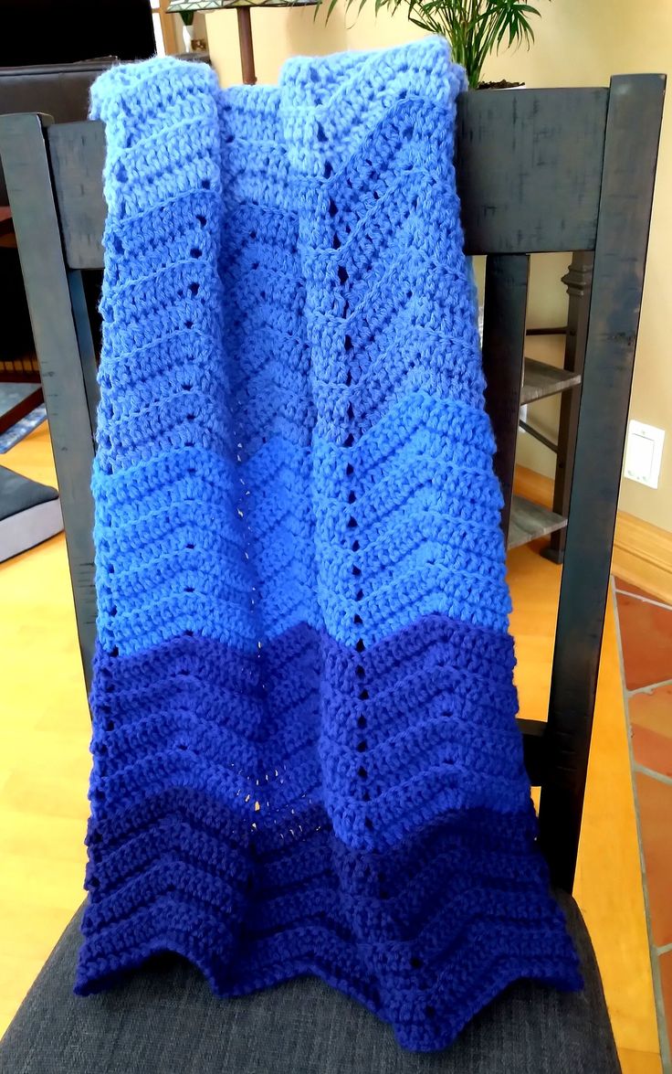 a blue crocheted blanket sitting on top of a chair