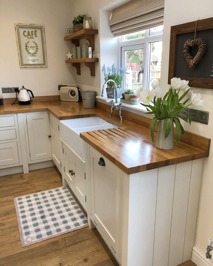 a kitchen with white cabinets and wooden counter tops, including a large farmhouse style sink