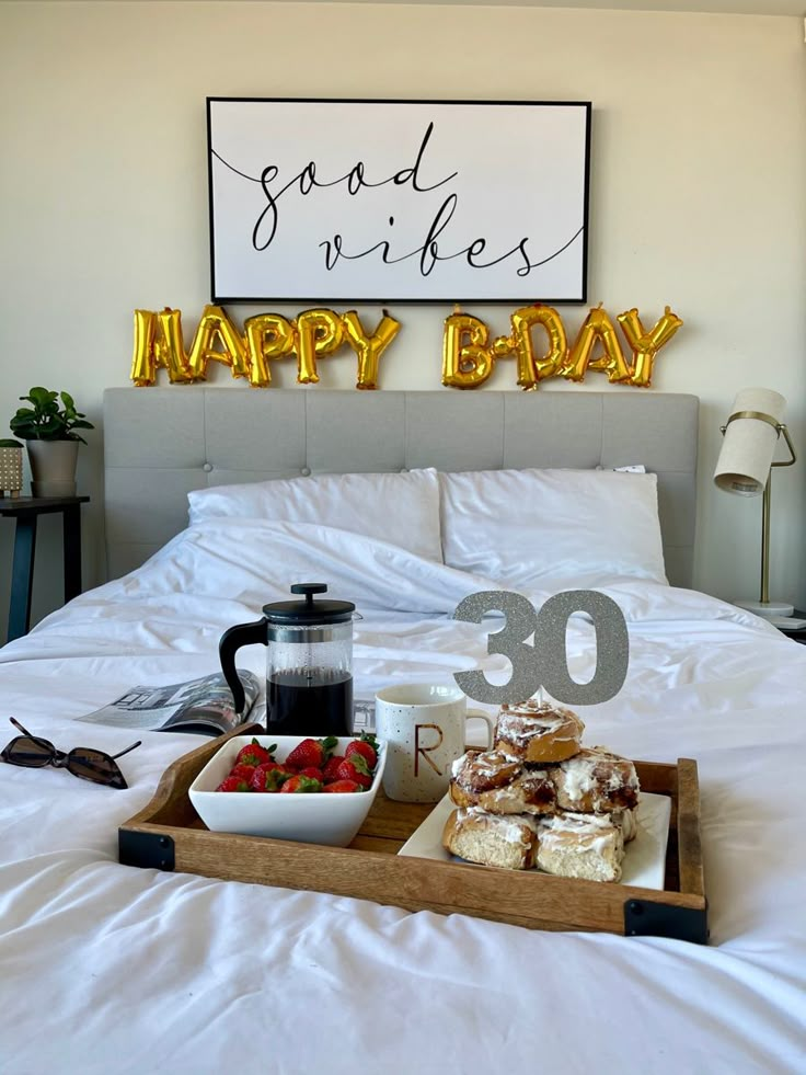 a tray with food on top of a bed next to a sign that says happy b - day