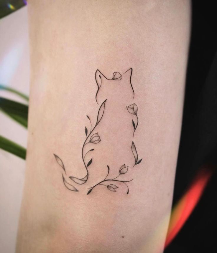 a woman's thigh with a tattoo of a cat and leaves on the side