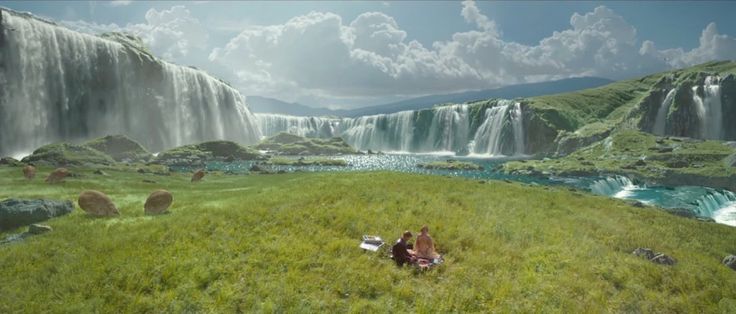 two people are sitting in front of a waterfall and looking at the water from below