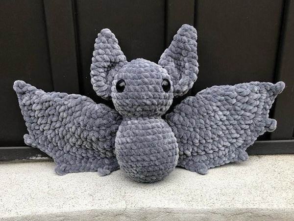 a gray stuffed animal sitting on top of a cement slab next to a black door