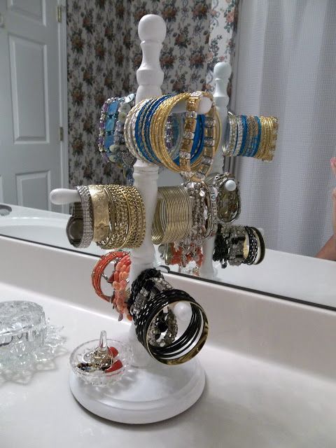 bracelets and rings are hanging from a rack in front of a mirror on a bathroom counter