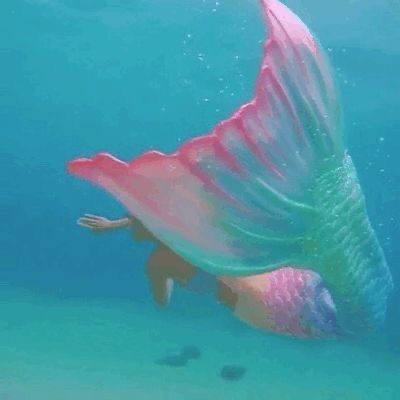 an underwater view of a mermaid swimming in the ocean with her tail spread out and wings outstretched