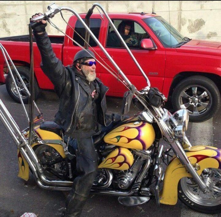 a man on a yellow and purple motorcycle with his arms up in the air while holding onto some metal bars