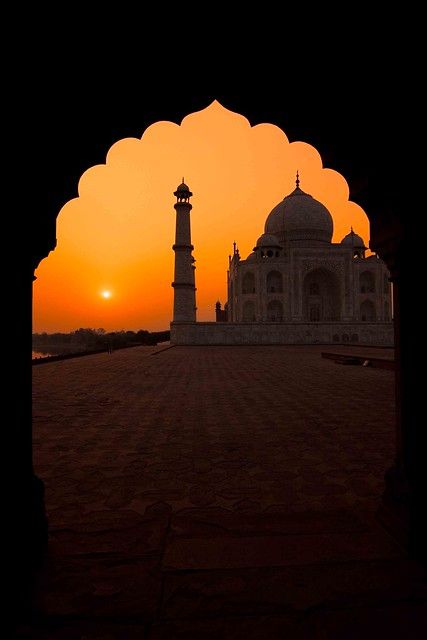 the sun is setting behind an archway in front of a building with two minalis