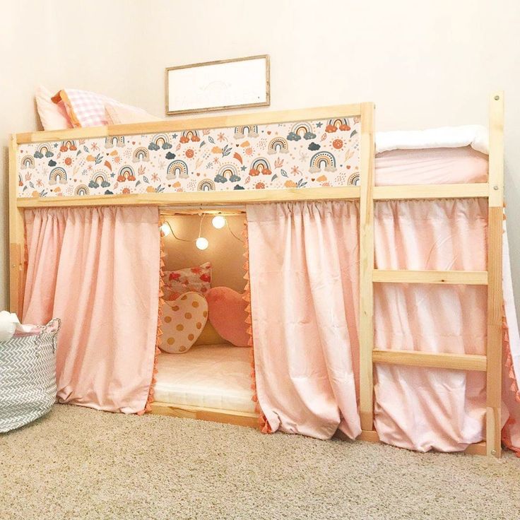 a child's bedroom with pink curtains and a wooden bunk bed