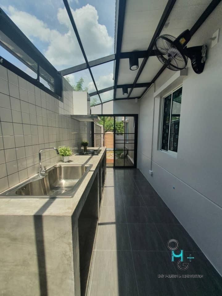 an outdoor kitchen with stainless steel sink and counter tops, under a glass roof area