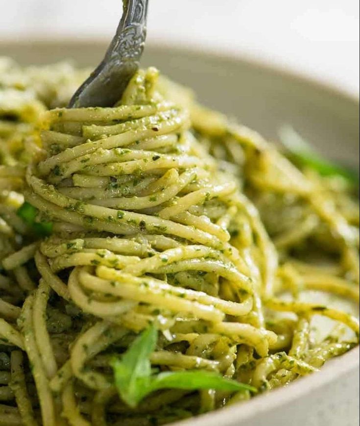 a close up of a bowl of pasta with pesto