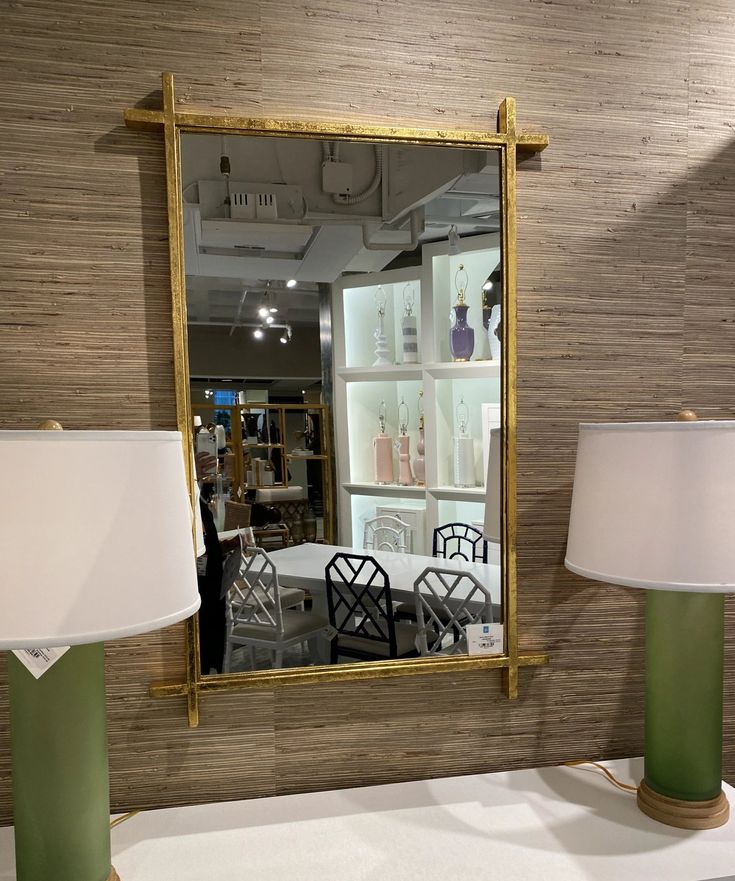 a large mirror sitting on top of a table next to two lamps and a lamp shade