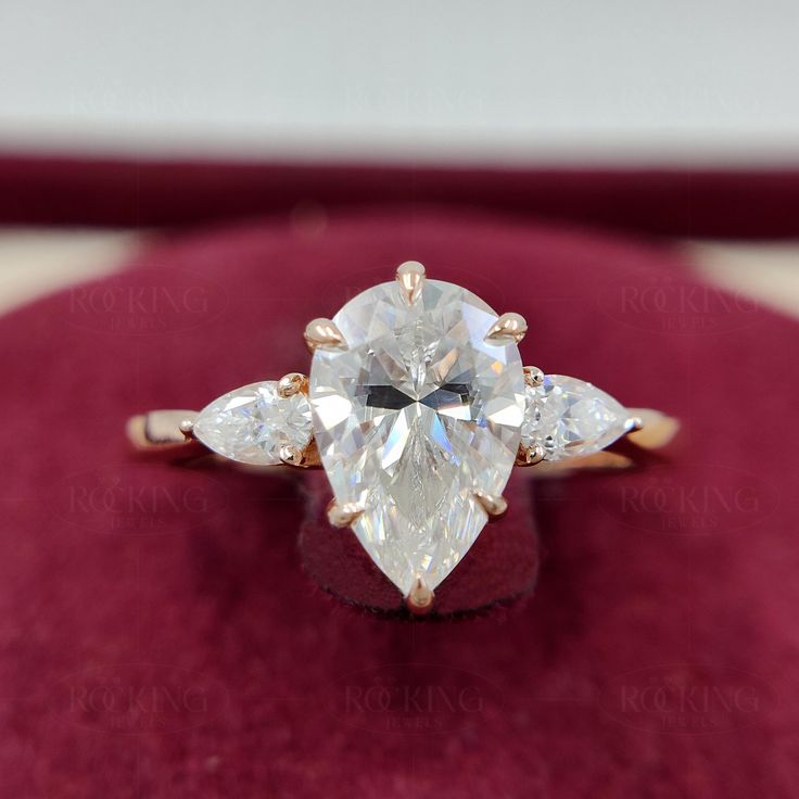 an engagement ring with three pear shaped diamonds in it on top of a velvet box