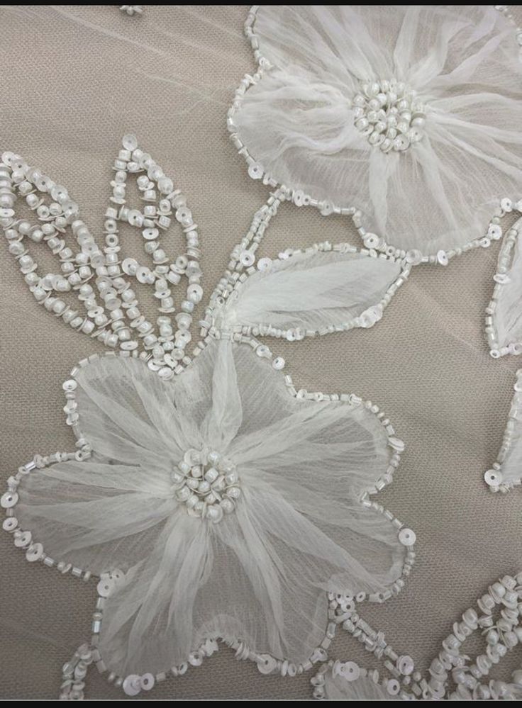 some white flowers and pearls are on a fabric material that looks like something out of fairy tale