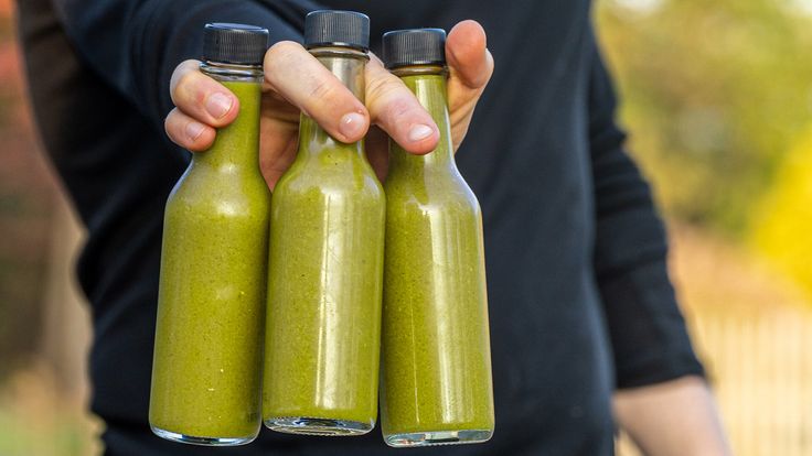 a person holding three bottles with green liquid in them and labeled 4 % spicer