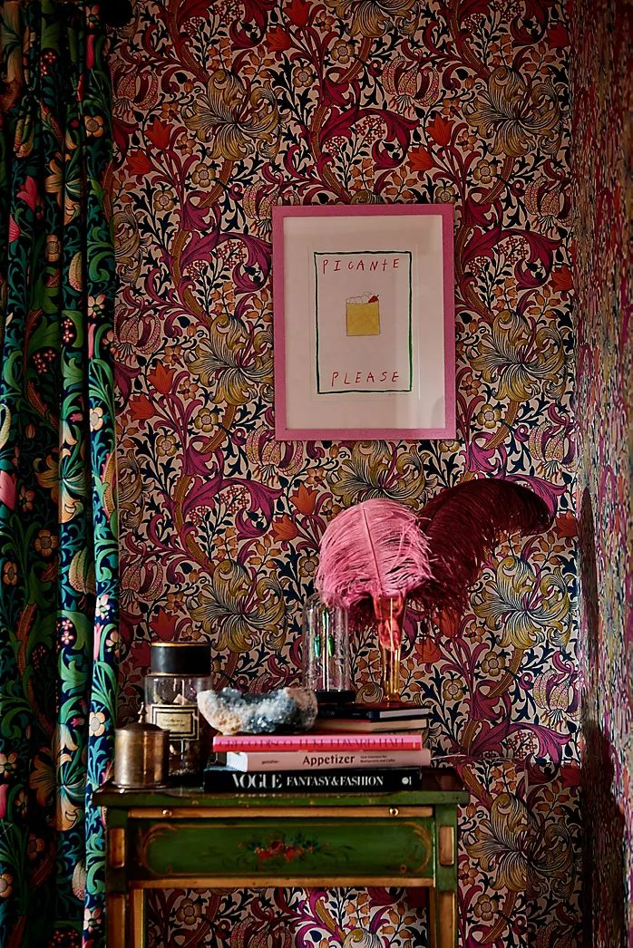 a table with some books on top of it in front of a floral wallpaper