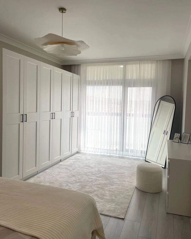 a bedroom with white furniture and large windows