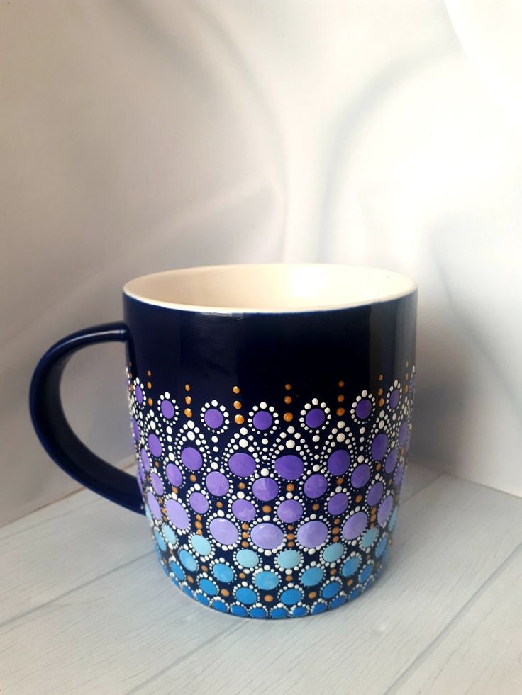 a blue and purple coffee cup sitting on top of a white table