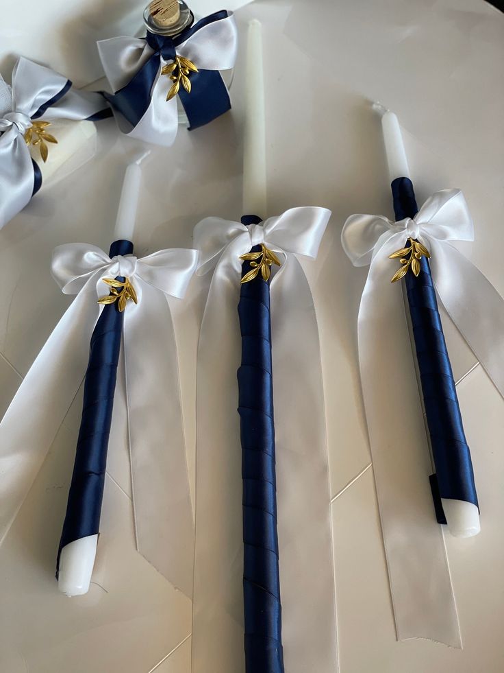 four blue and white ribbons tied to each other with gold accents on them, sitting on a table