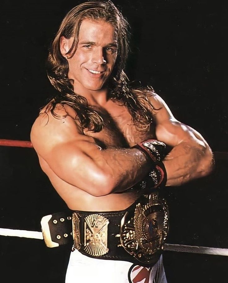 a man with long hair and no shirt holding a wrestling belt