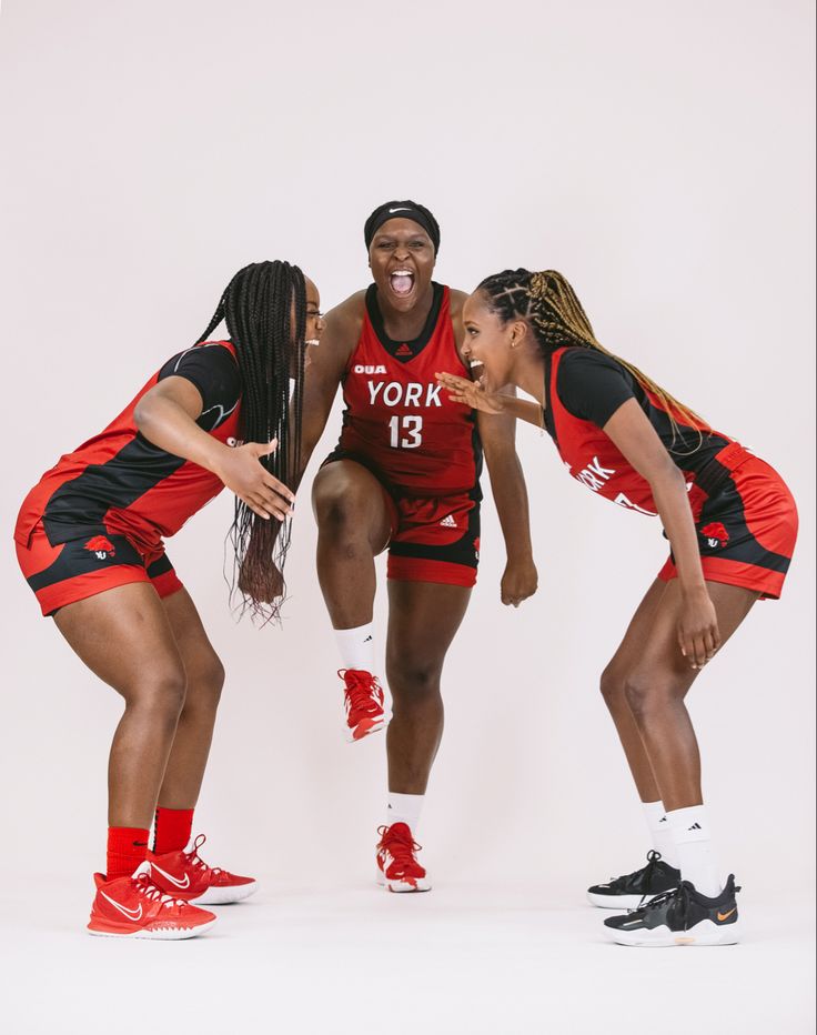 three women in red and black basketball uniforms posing for a photo