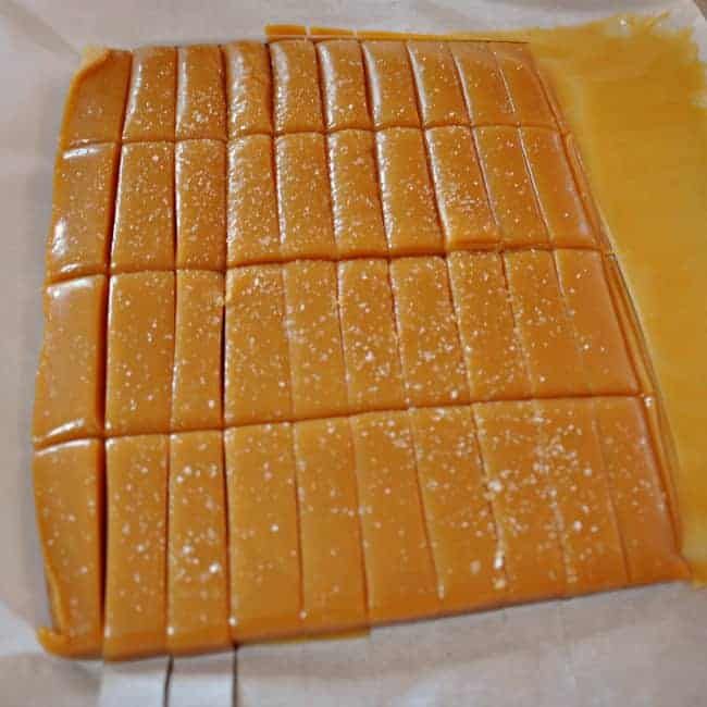 some pieces of cheese sitting on top of a piece of wax paper with yellow liquid