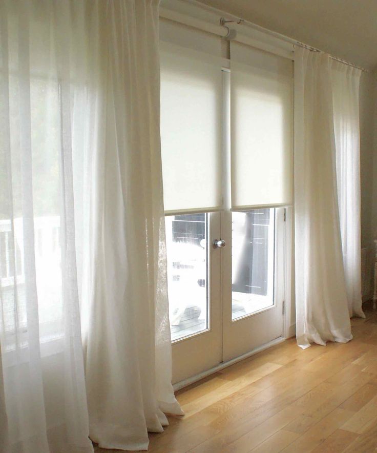 an empty room with wooden floors and white curtains