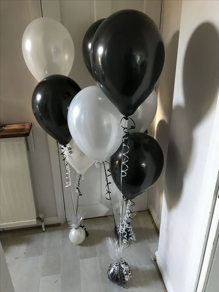 black and white balloons are on the floor in front of a door with silver foil decorations