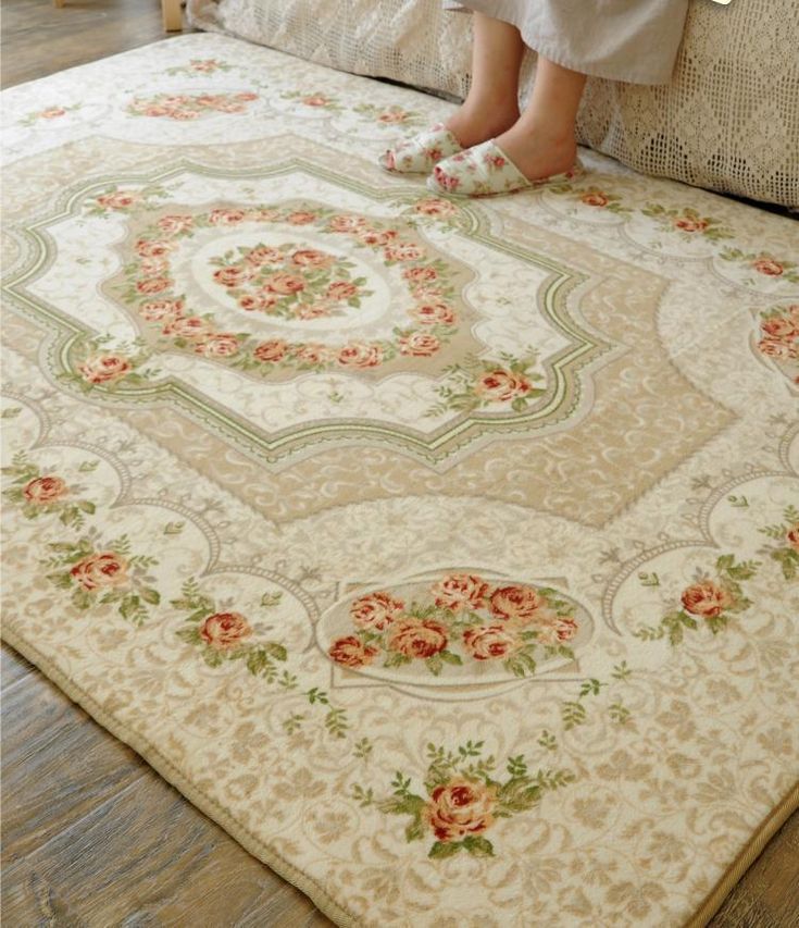 a woman sitting on top of a bed in front of a white rug with pink flowers