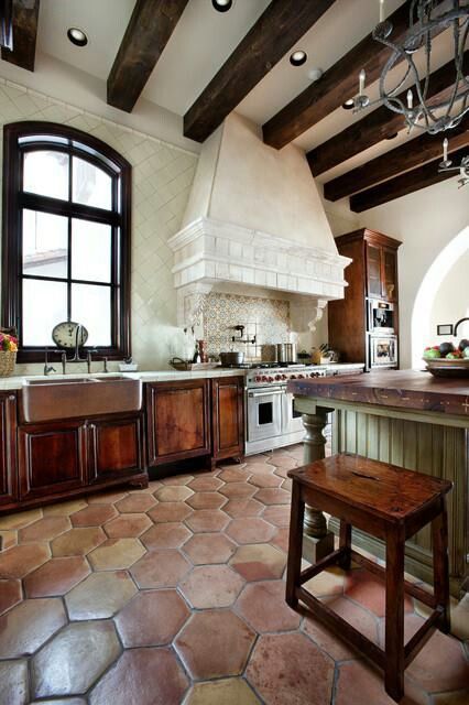 a large kitchen with an island in the center and wooden cabinets on both sides, along with stone flooring