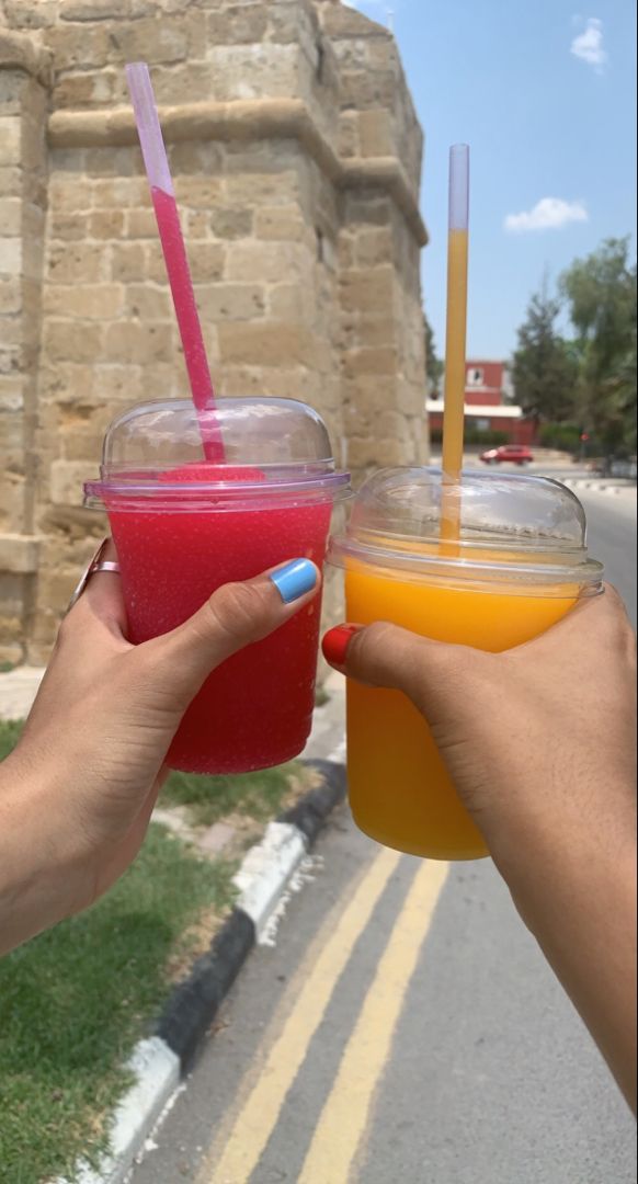 two people holding up cups with drinks in them