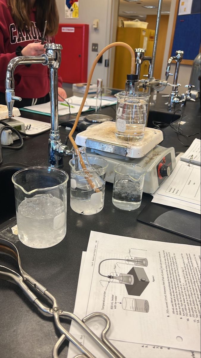 a table topped with glasses and beakles filled with liquid next to papers on top of it