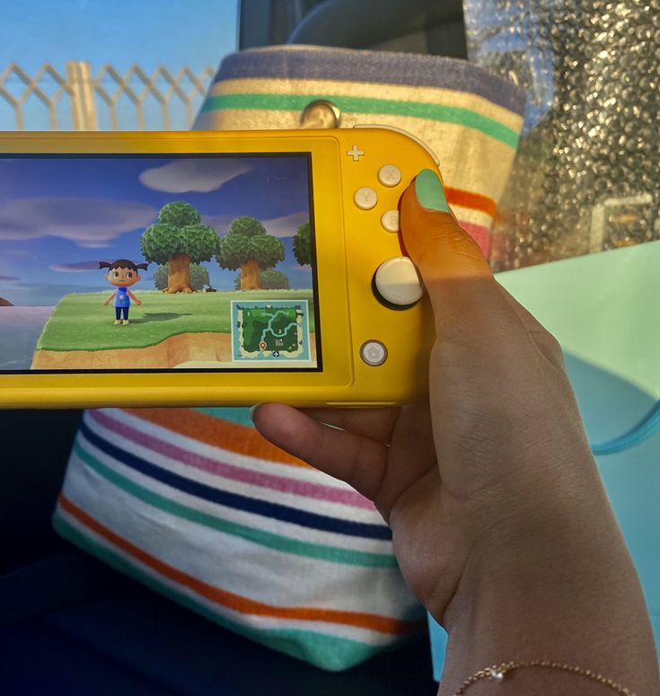 a person holding a yellow nintendo wii game controller in their left hand and playing on the screen