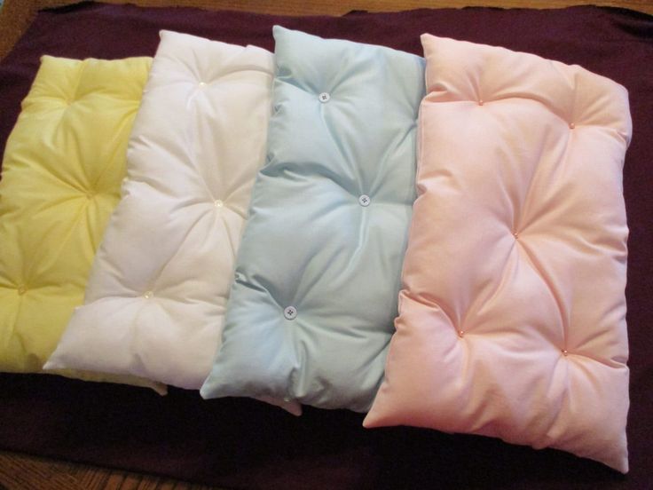 four different colored pillows sitting on top of a wooden floor next to a brown blanket