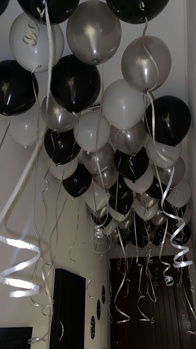 a bunch of black and white balloons hanging from the ceiling in front of a door