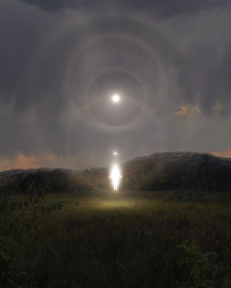 a man standing in the middle of a field under a dark sky with an eyeball