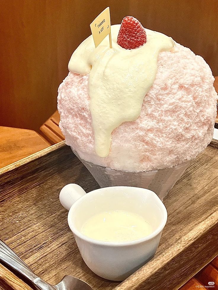 there is a cupcake with cream and strawberries on the top, next to a bowl of yogurt