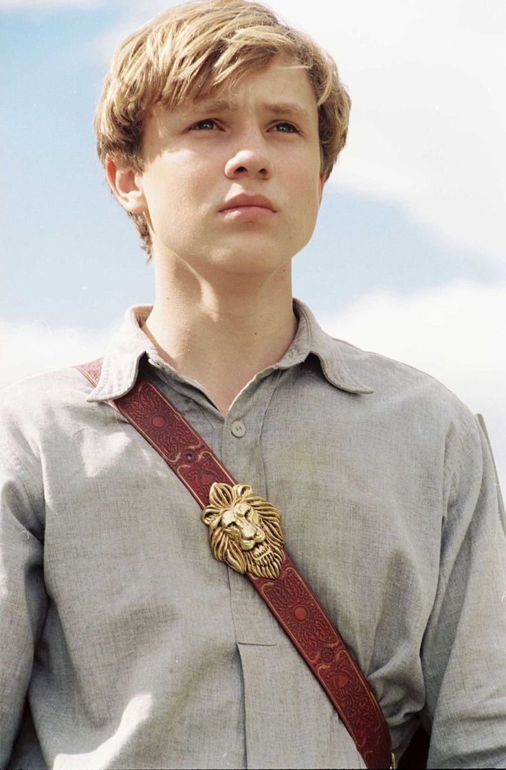 a young man wearing a lion head brooch on his neck and holding a camera