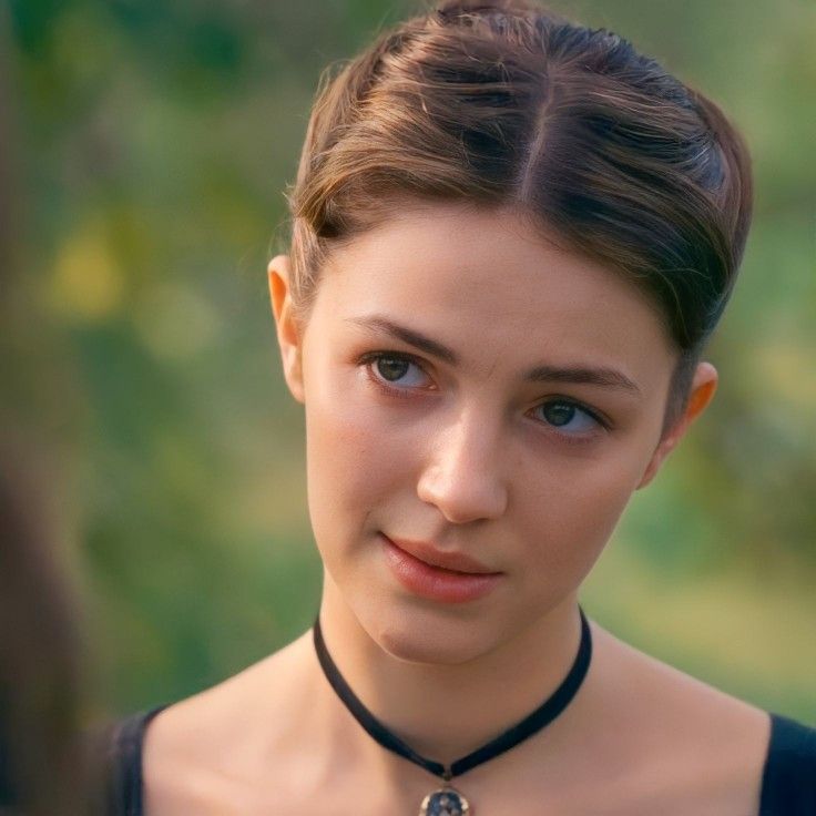 a close up of a person wearing a necklace with an evil look on her face