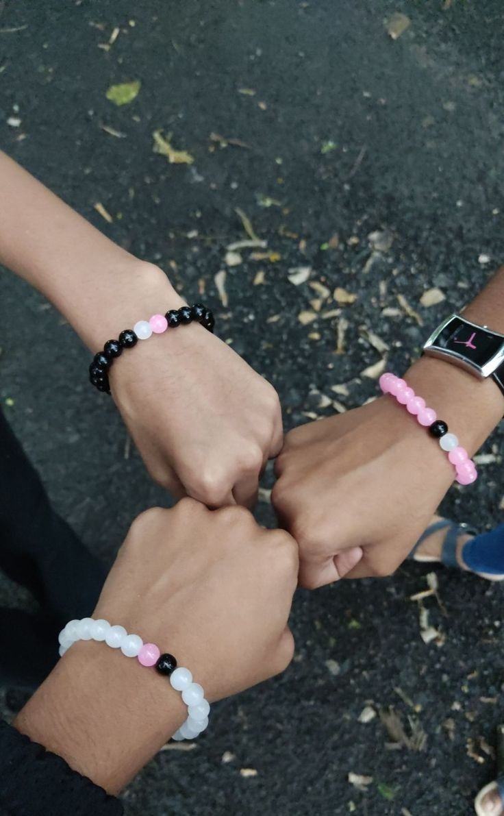 two people holding hands while standing next to each other with bracelets on their wrists